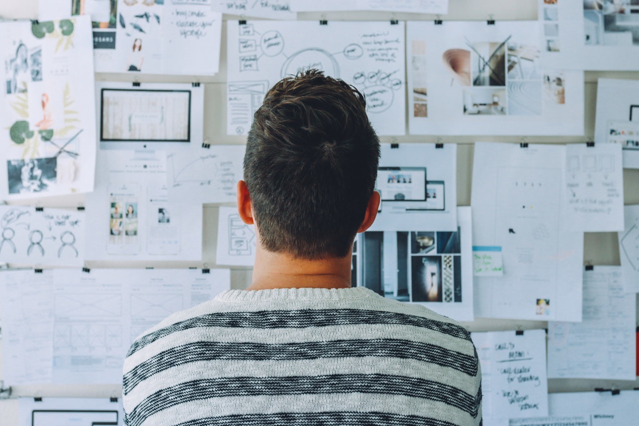 Guy looking at a collage pinned on a cork board
