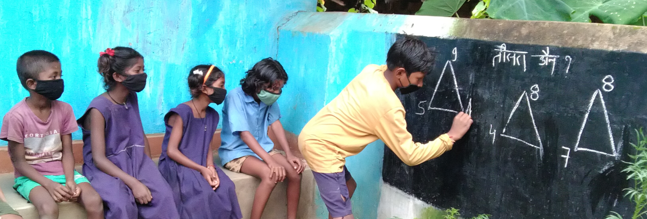 Student writes on chalkboard in front of other students.