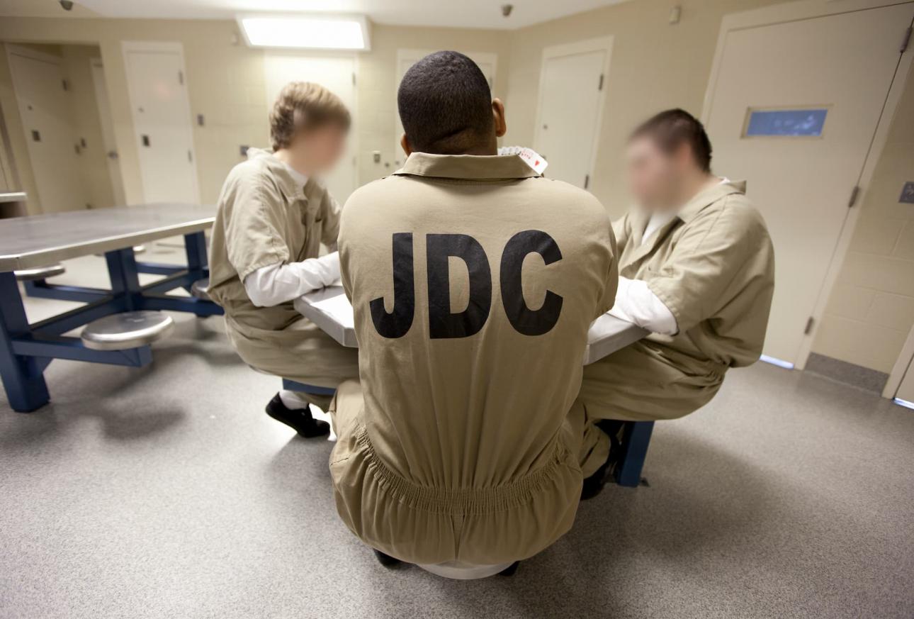 Incarcerated young men sitting around a table in prison