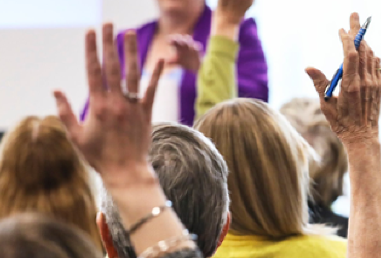 Image depicts a community networking event with a cropped in focus around hands being raised