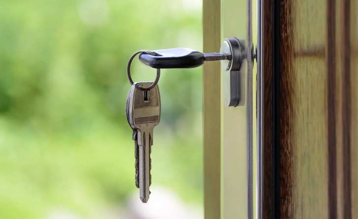 Image depicts a key hanging from key lock of a door